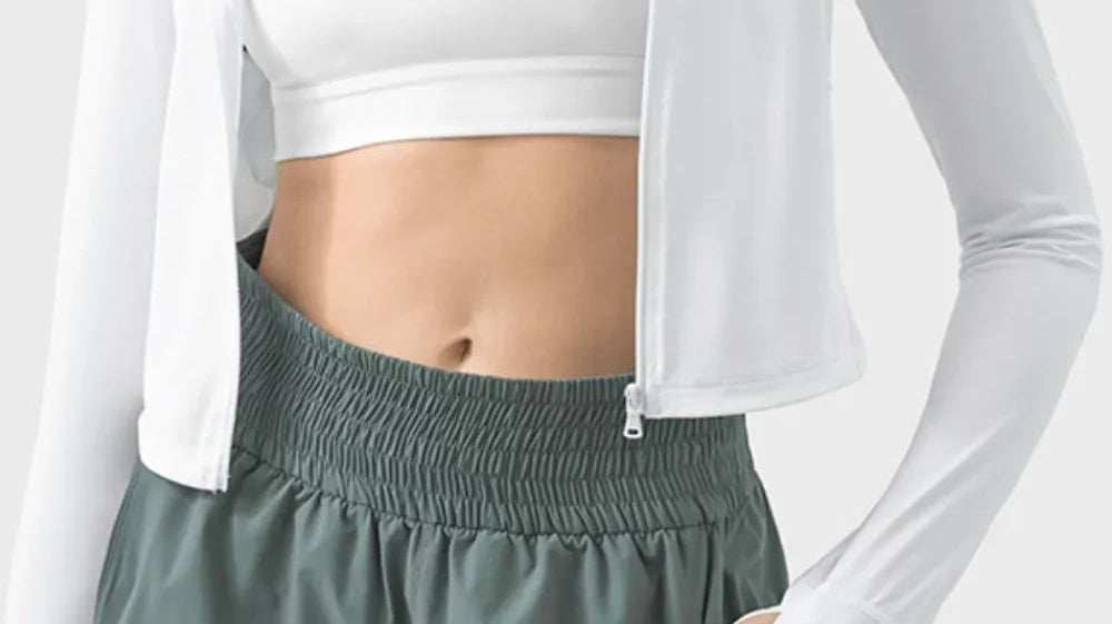 Woman in white zip hoodie and sports bra with green shorts, Love Classic activewear