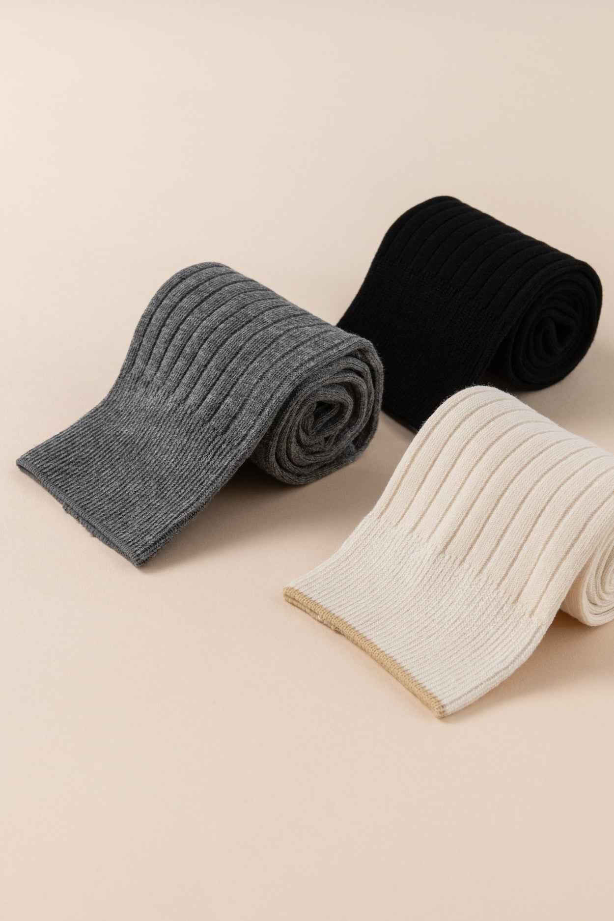 Three ribbed knit tights in gray, black, and cream from Love Classic on a neutral background.