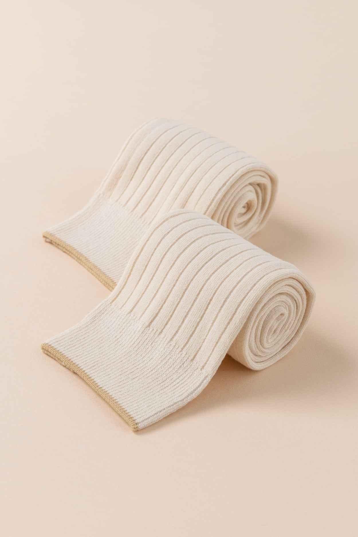 Pair of cream ribbed knit socks on beige background, Love Classic style accessory