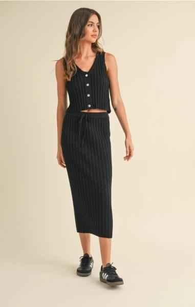 Woman wearing a black ribbed knit buttoned crop top and midi skirt set from Love Classic