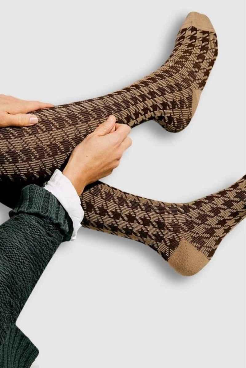 Brown and beige houndstooth pattern socks from Love Classic on a person’s legs