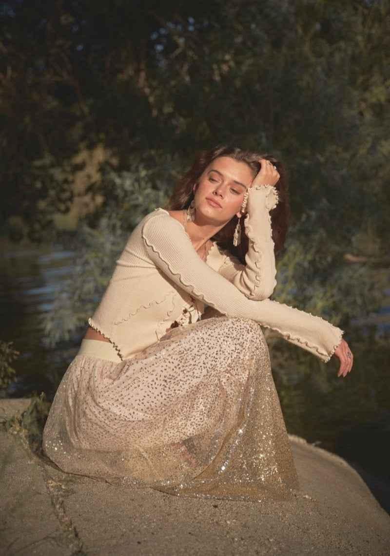 Woman in cream ruffle top and sparkly tulle skirt sitting outdoors, Love Classic fashion