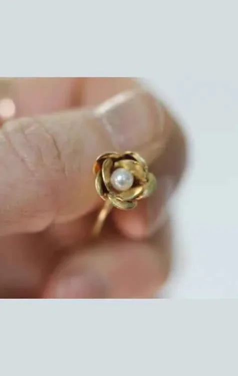Hand holding gold flower ring with pearl center, Love Classic high quality jewelry