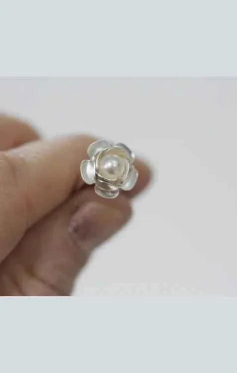 Hand holding silver flower ring with pearl center, Love Classic high quality jewelry