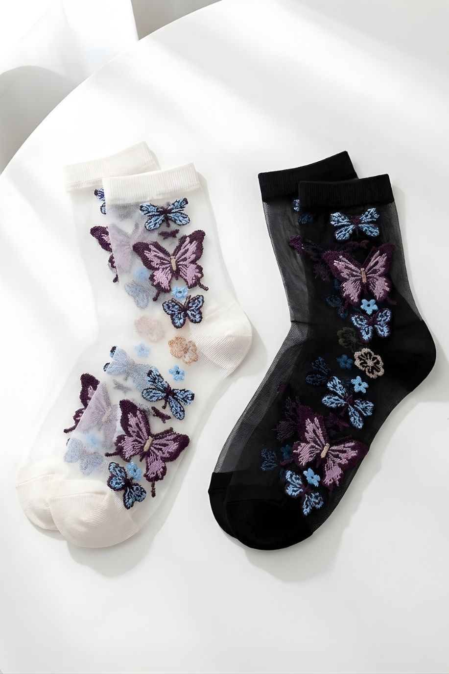Butterfly Sheer Socks 2-Pack featuring two color options in sheer mesh fabric with detailed butterfly embroidery, displayed flat on a clean white surface.