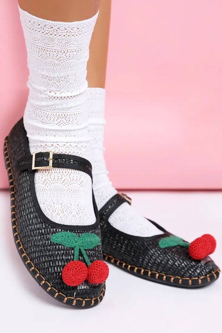 Cherry Accent Mary Jane Flats, black woven Mary Jane flats with buckle strap and red cherry embellishment, paired with white lace socks against a soft pink backdrop, highlighting the textured finish and playful design.