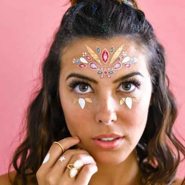 Woman with decorative face gems and rings against pink background, Love Classic style