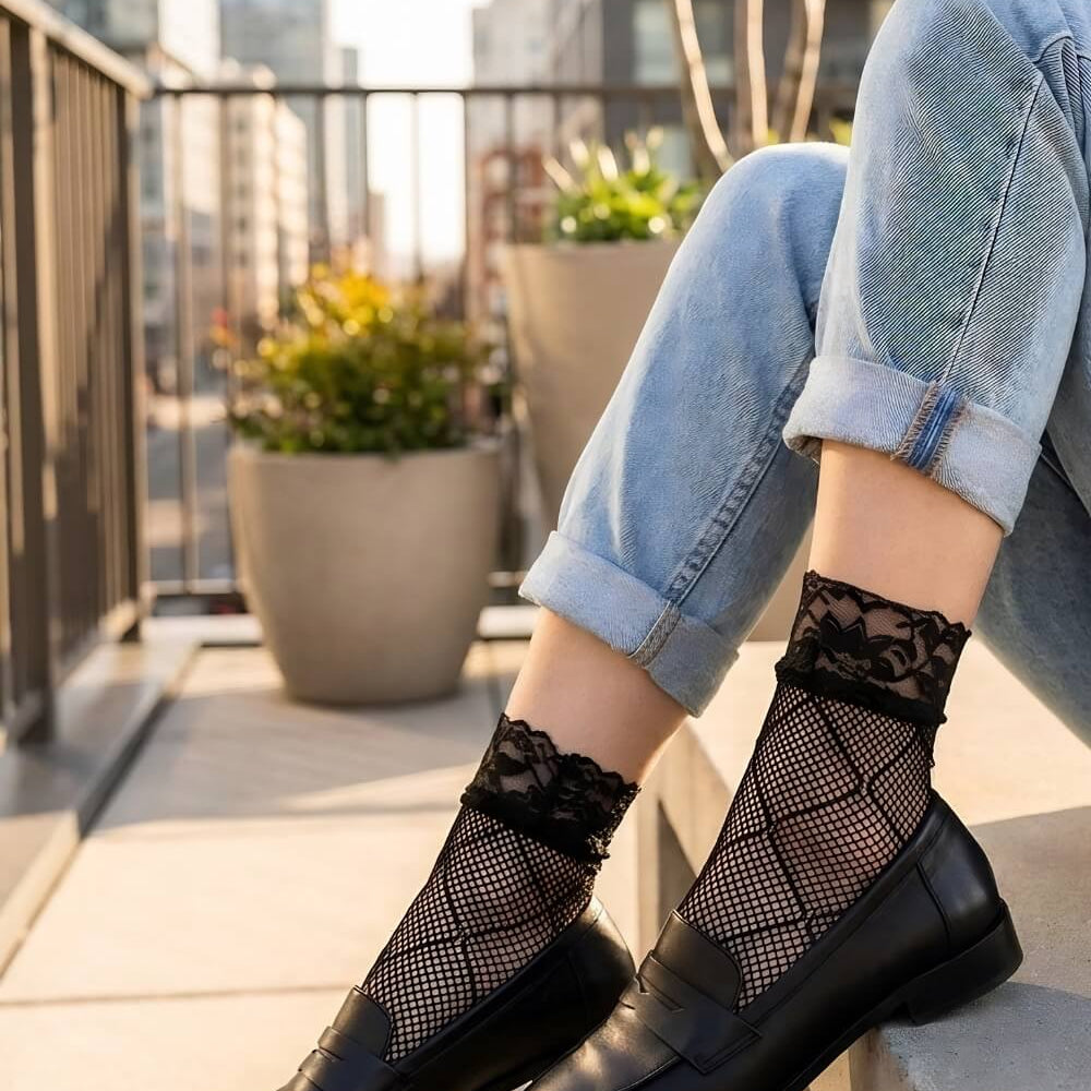 Diamond Lace Fishnet Socks featuring a fine fishnet weave with bold diamond-pattern detailing and delicate floral lace cuffs, styled with rolled light-wash jeans and black loafers on a rooftop terrace with a city skyline backdrop in warm golden sunlight for a chic street-style look.