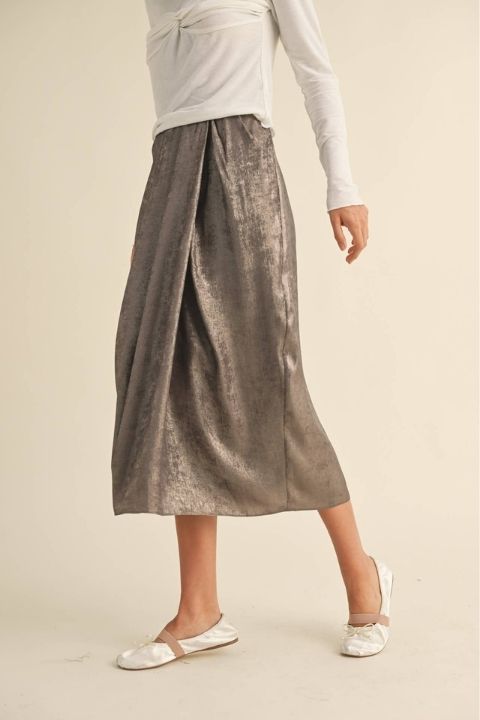 Metallic Fabric Pleat Detailed Skirt, side view showing a high waist, soft front pleat detail, fluid midi length, and luminous metallic finish styled with a long sleeve top and flat shoes.