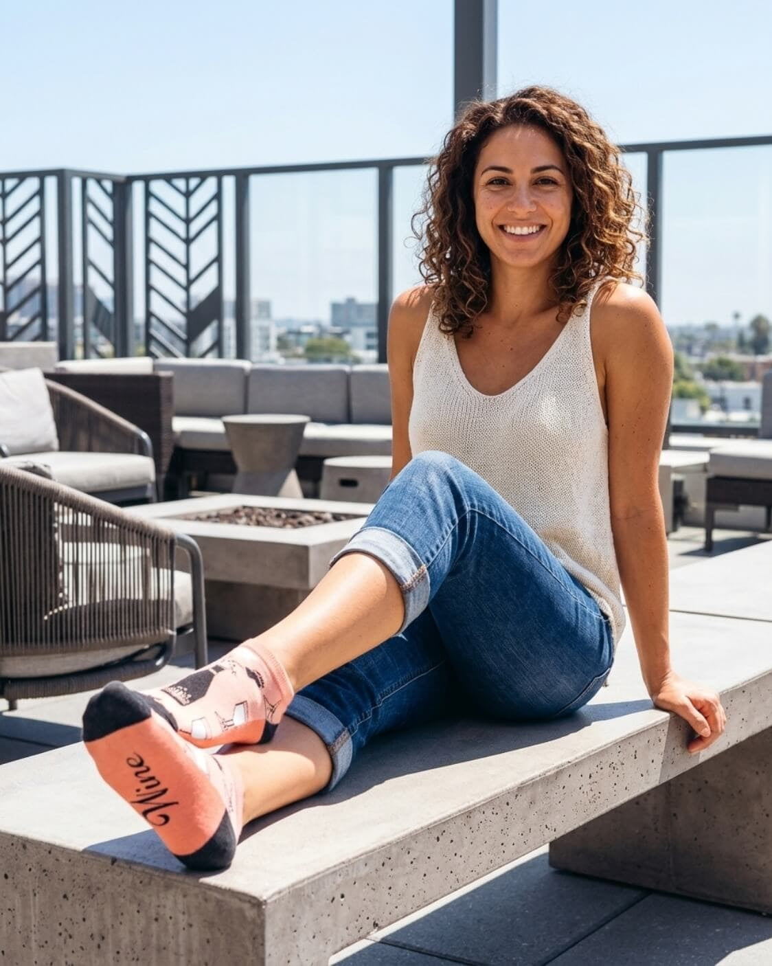 Shorty Socks, Wine Down featuring a low ankle fit with wine bottle graphics, glass motifs, dark toe panels, and “Wine” text on the sole, worn while seated on a rooftop terrace, highlighting playful casual styling.