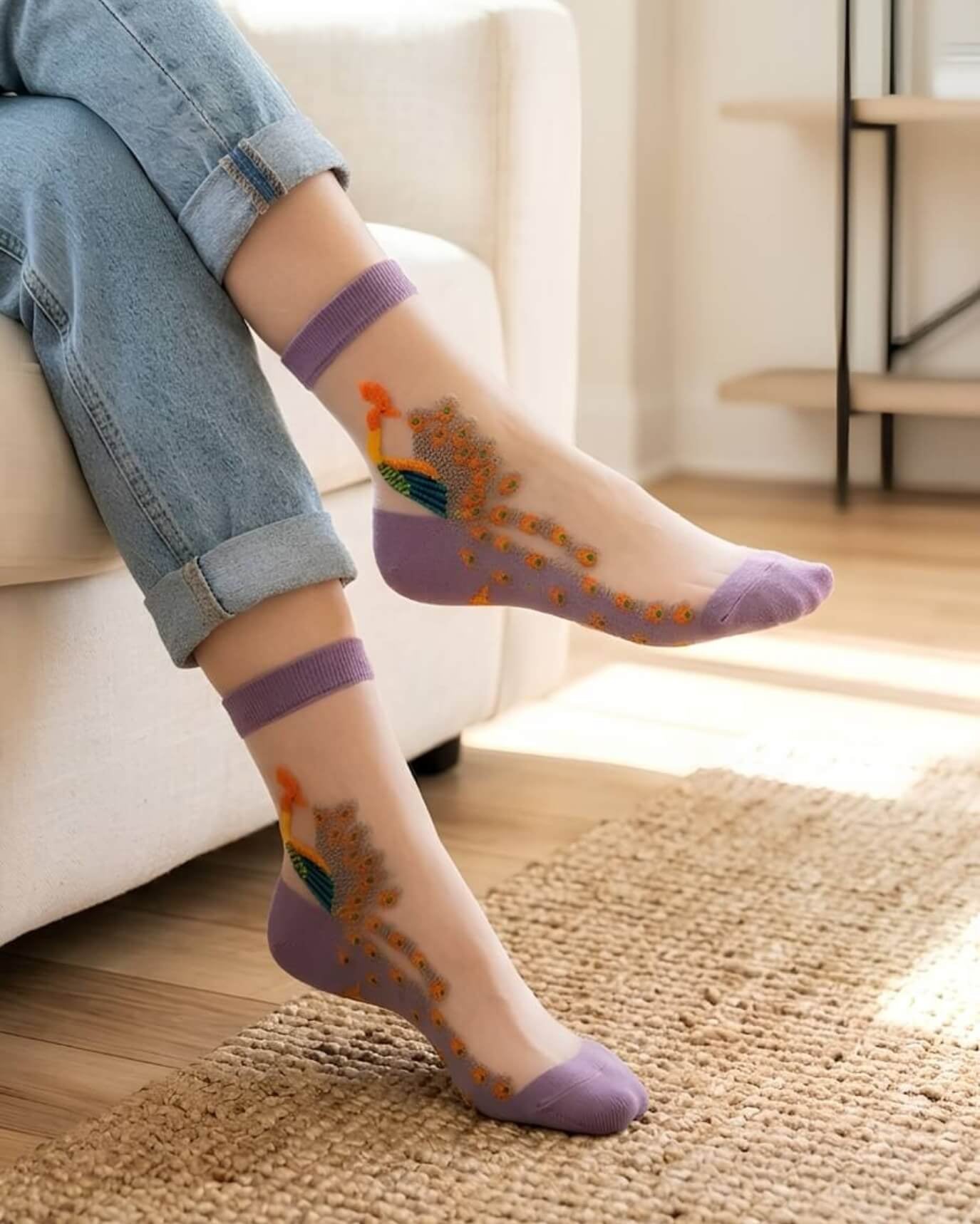 4-Pack Peacock Sheer Mesh Socks featuring lightweight transparent mesh fabric with embroidered peacock motifs and soft purple trim, worn indoors with rolled denim jeans in a bright living space, highlighting comfort and playful everyday styling.