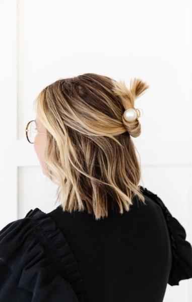 Woman with short blonde hair in a black top wearing a pearl hair clip, Love Classic style