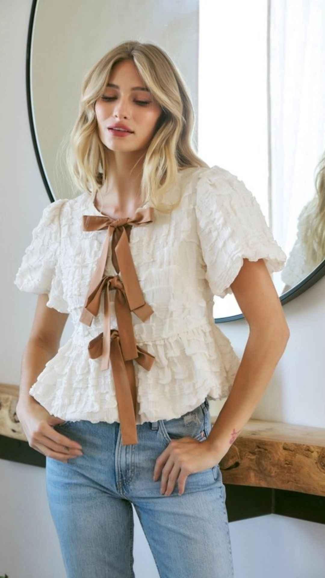 Woman wearing a ruffled white blouse with brown ribbon bows and blue jeans, Love Classic style