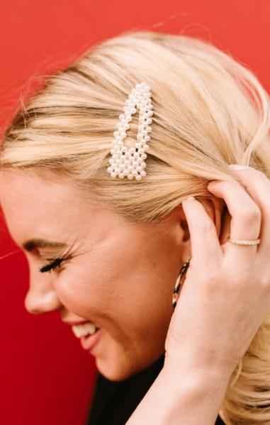 Smiling woman with pearl hair clip against red background, Love Classic style accessory