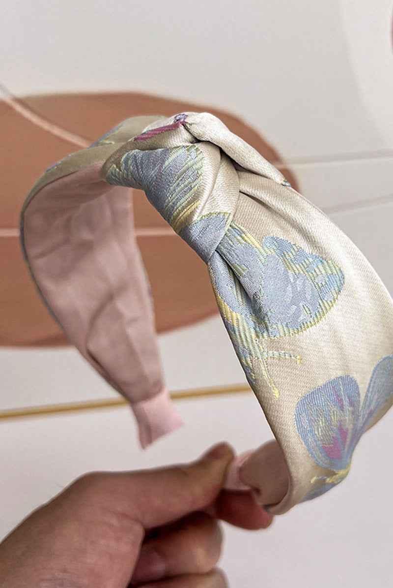 Hand holding floral knotted headband in pastel colors from Love Classic collection