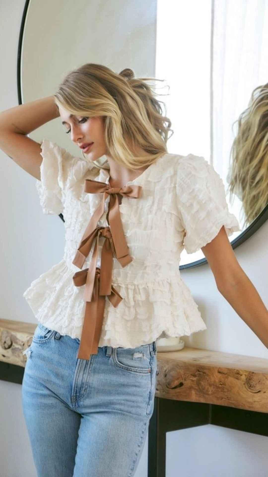 Woman wearing a ruffled white blouse with brown bows and light blue jeans, Love Classic style