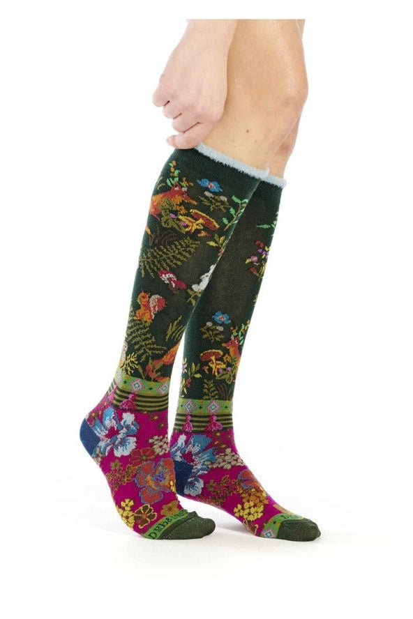 Woman wearing knee-high floral socks with colorful botanical pattern in green, pink, and blue.