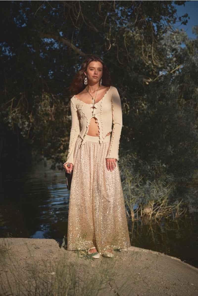 Woman in cream ruffle top and sequin maxi skirt by a lake, Love Classic fashion style