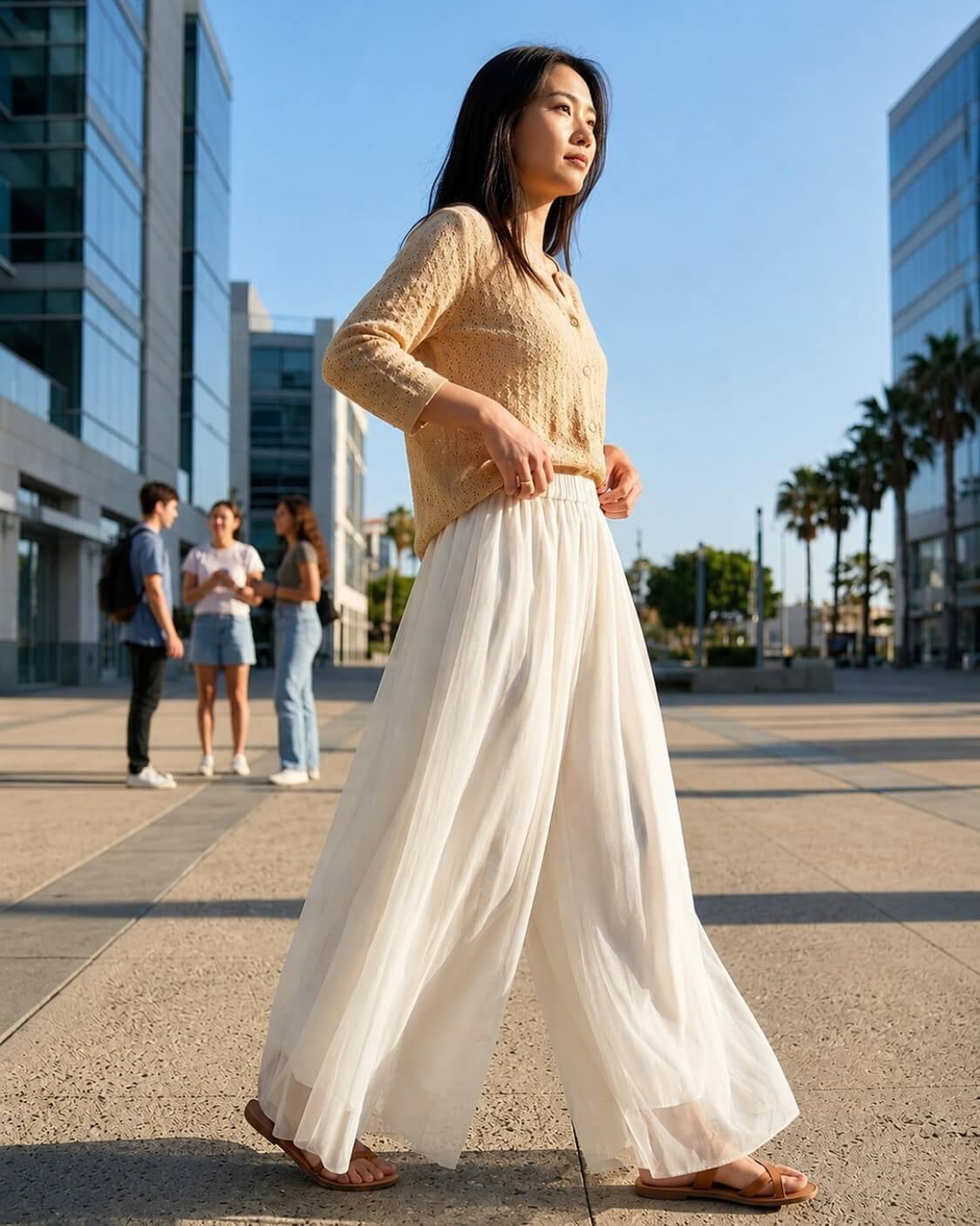 Chiffon Wide Leg Pant featuring a high-waist fit, sheer layered wide legs, and soft vertical pleating, worn with a button-front top and sandals in an open urban plaza, highlighting graceful movement and relaxed styling.