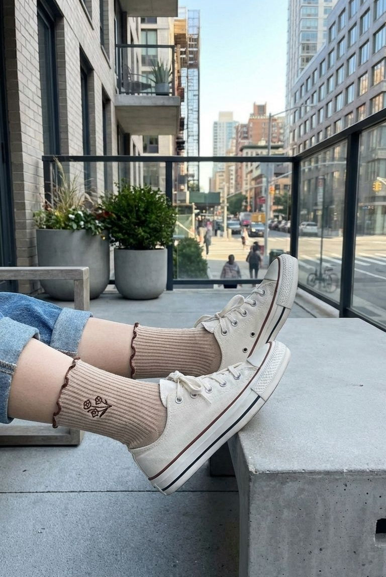 3-Pack Floral Bloom Ribbed Ruffle Crew Socks, outdoor balcony view showing ribbed socks with subtle floral detail and ruffled edge styled with sneakers and rolled jeans in a modern urban setting.