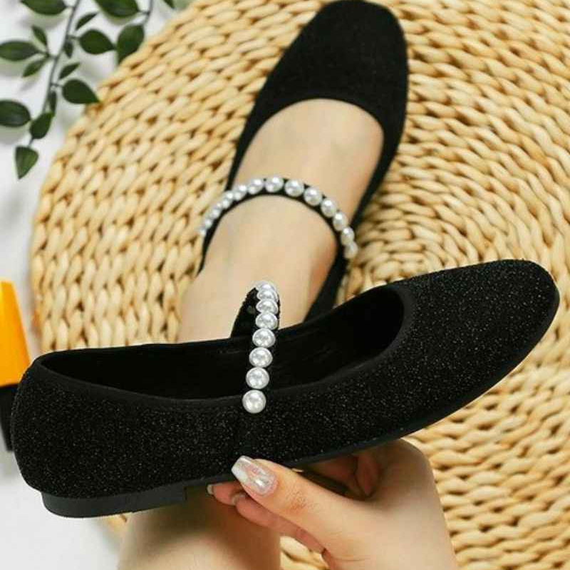 Black Mary Jane flats with pearl strap, Love Classic style, displayed on woven mat