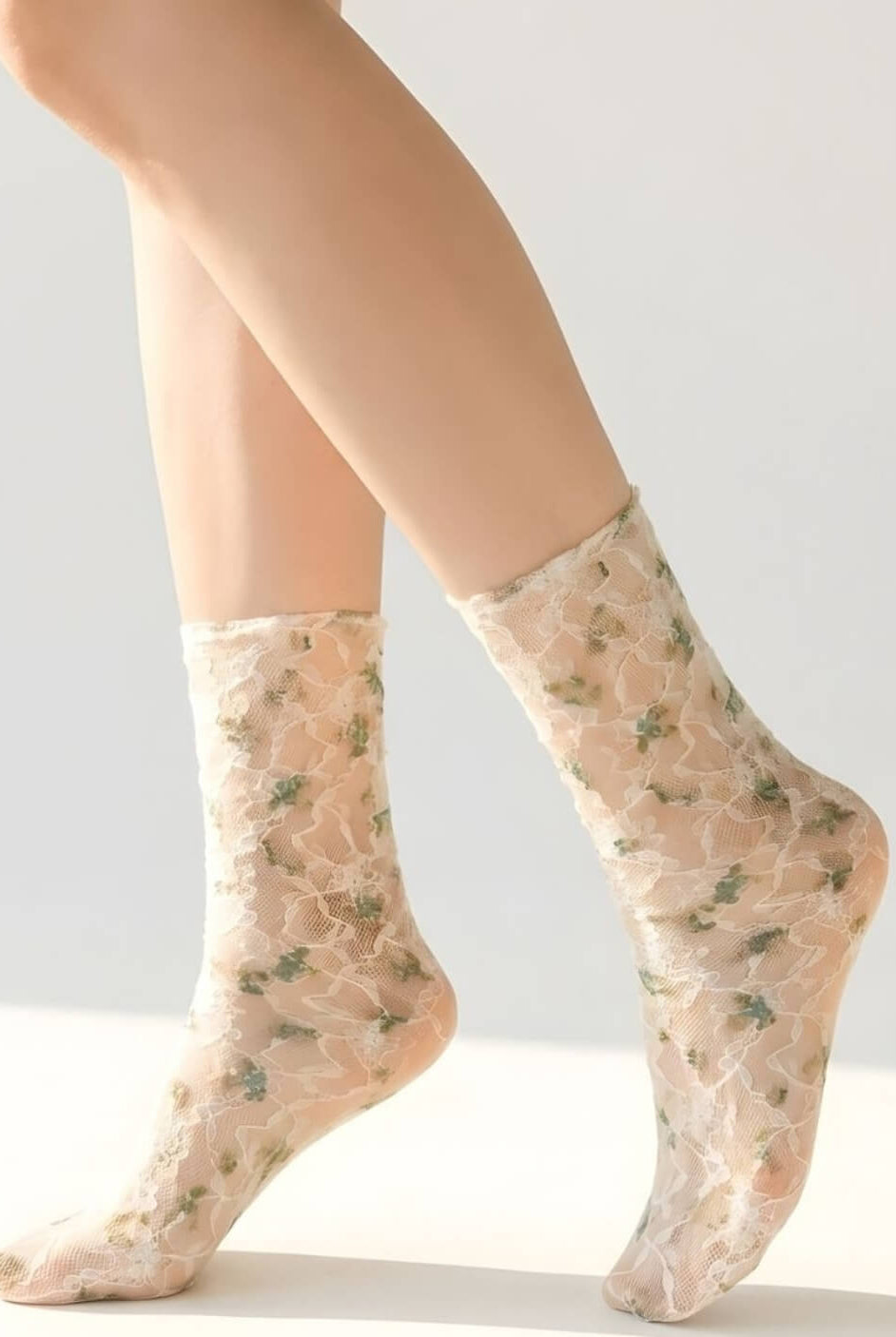 Floral mesh sheer socks in a muted green floral pattern, styled on both feet in a clean studio setting to highlight the soft mesh fabric and delicate lace details.