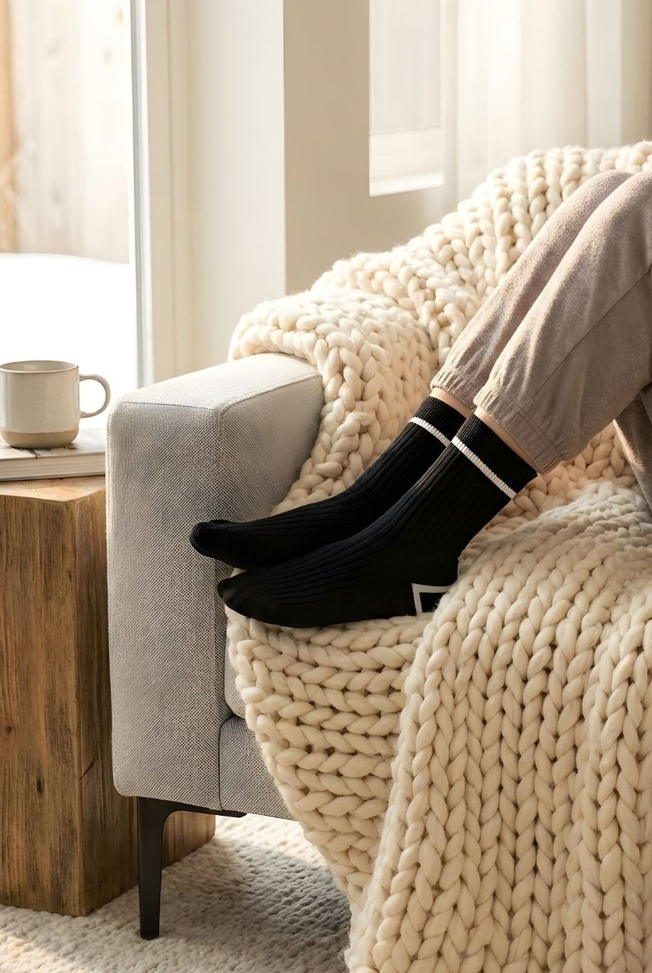Classic Ribbed Crew Socks with Contrast Trim, black ribbed crew socks with white contrast trim worn with neutral loungewear, resting on a sofa with a chunky knit throw, emphasizing comfort and everyday wear styling.