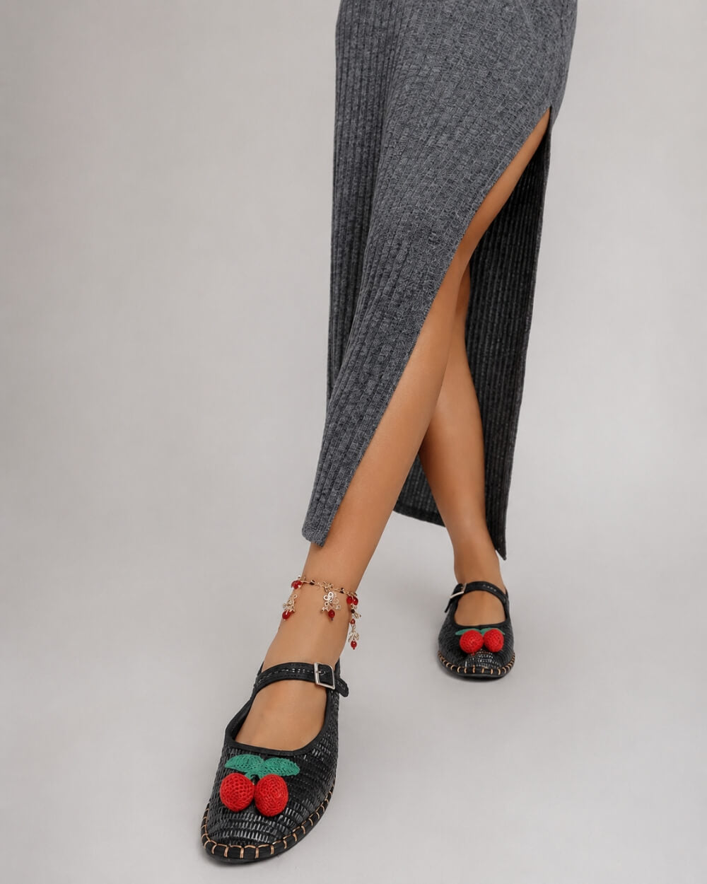 Cherry Accent Mary Jane Flats, black textured Mary Jane flats with cherry accent and buckle strap, paired with a grey slit midi dress and charm anklet, emphasizing the feminine silhouette and everyday styling.