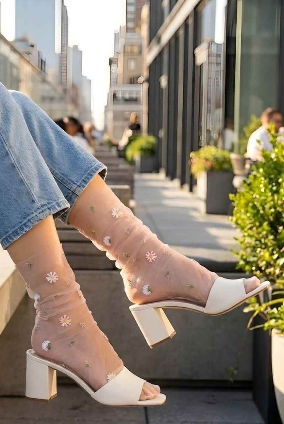 Sheer Garden Daisy Crew Socks in nude sheer fabric with embroidered daisies, styled with heeled mules and jeans in an urban setting.