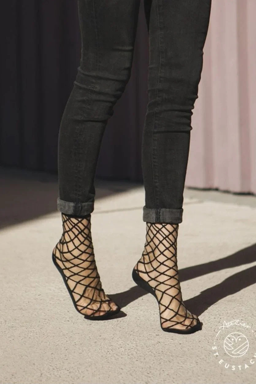 Woman wearing black fishnet socks and black jeans, stylish Love Classic fashion