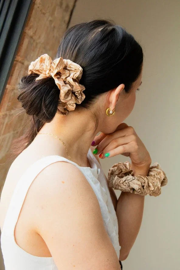 Woman wearing beige scrunchies in hair and on wrist, Love Classic style accessories