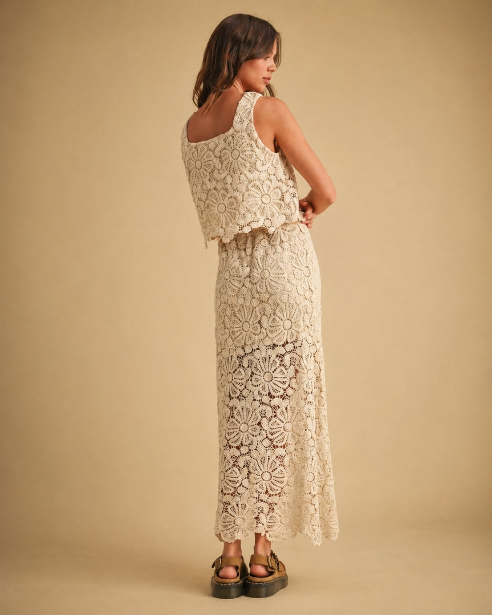 Crochet Knitted Skirt featuring a full length floral crochet pattern with a sleeveless layered back and scalloped edges, captured from the back in a relaxed standing pose with chunky woven sandals against a minimal neutral backdrop, highlighting handcrafted texture and flowy structure.