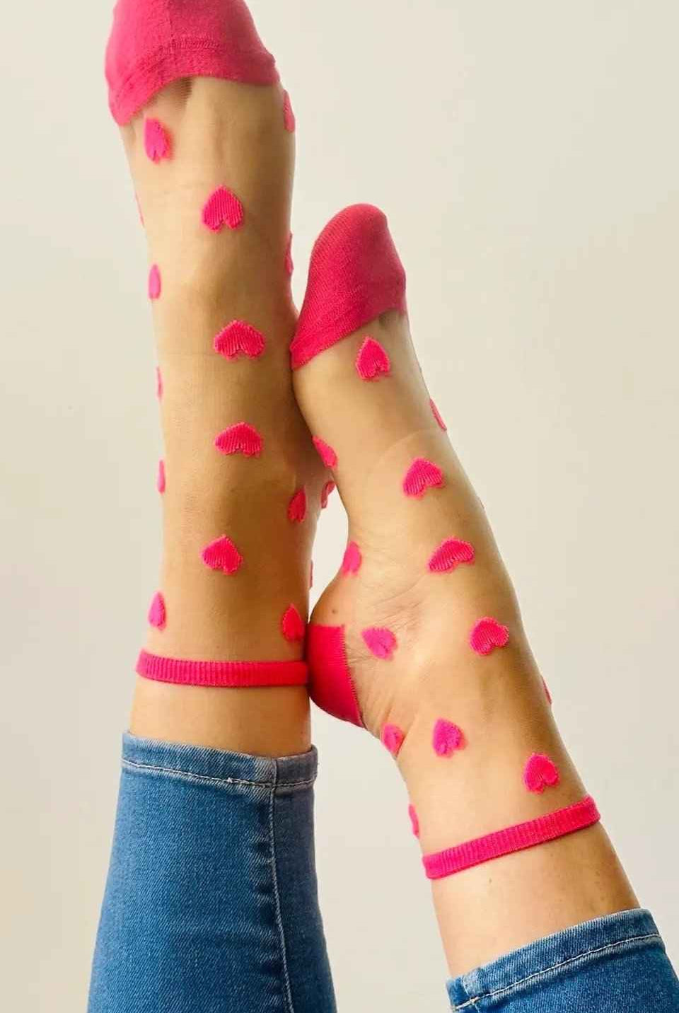 Woman wearing sheer socks with pink heart patterns from Love Classic, paired with jeans