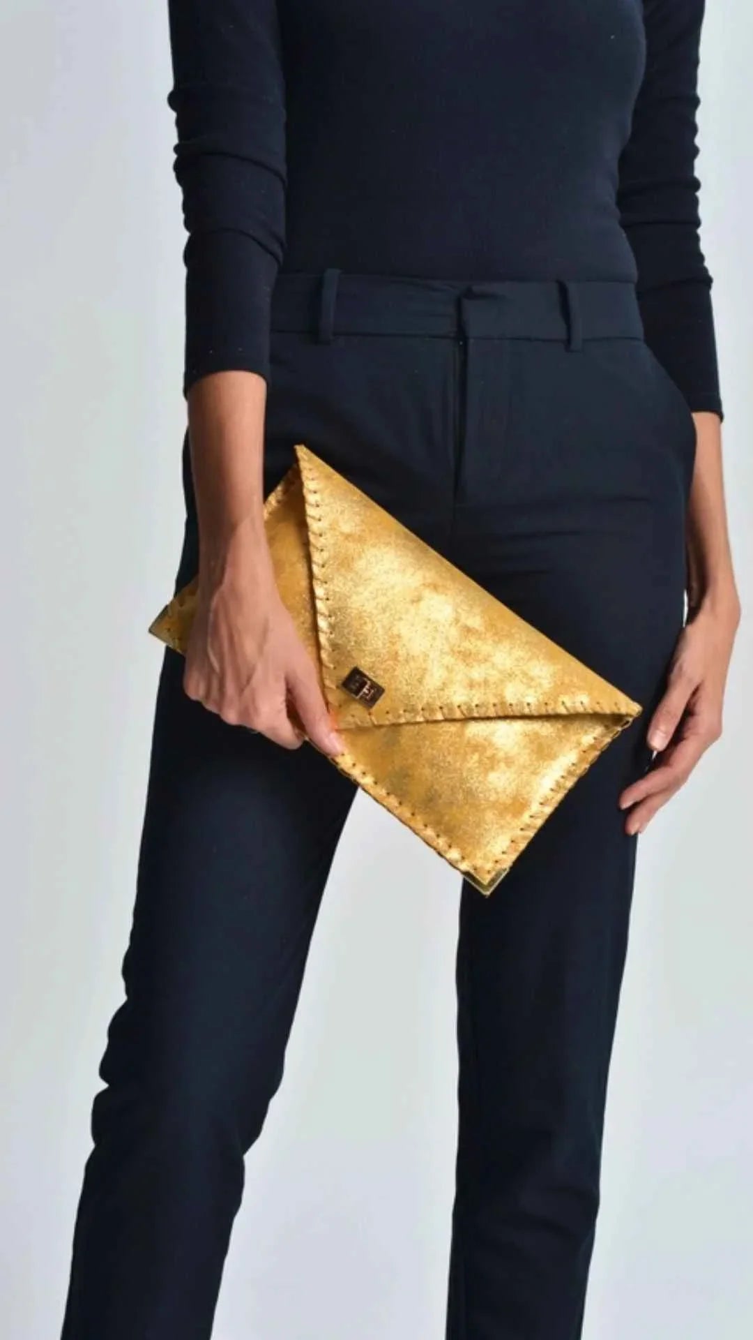 Woman in black outfit holding a gold envelope clutch bag, Love Classic fashion style