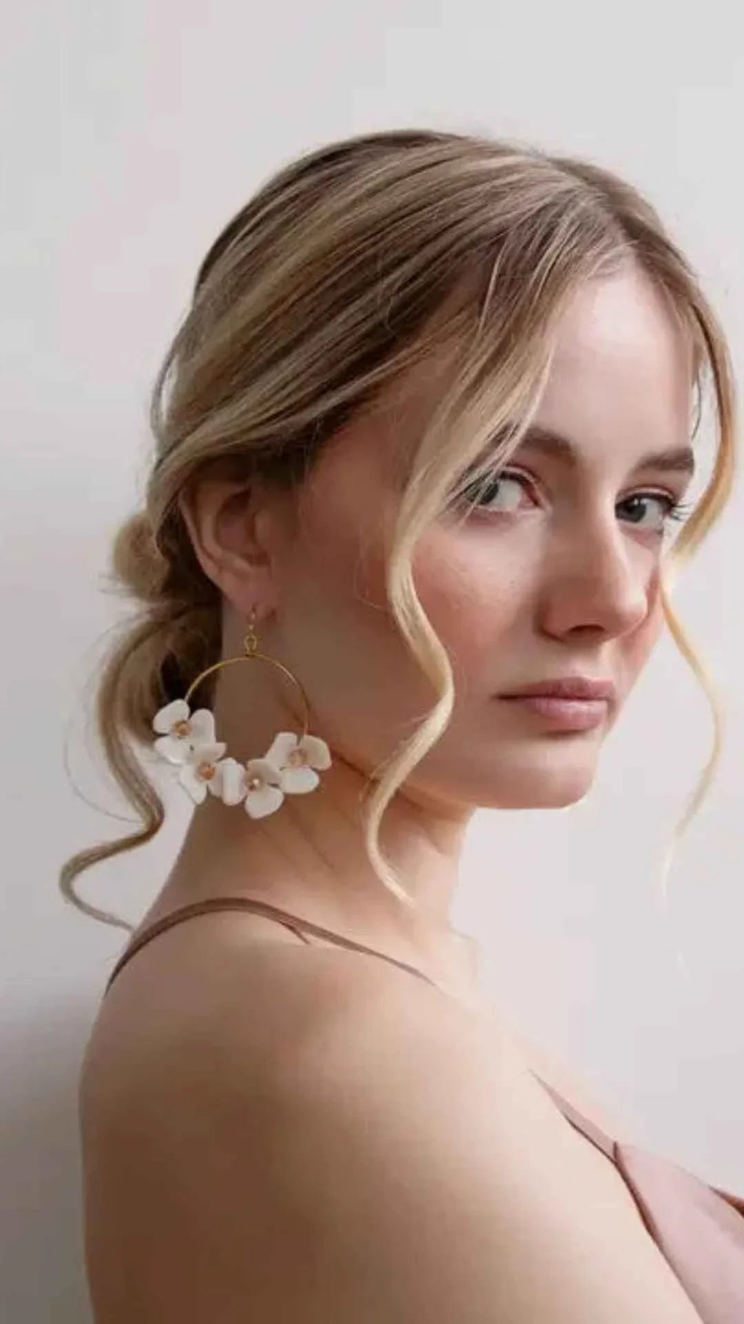 Woman wearing large gold hoop earrings with white flower accents, Love Classic style jewelry