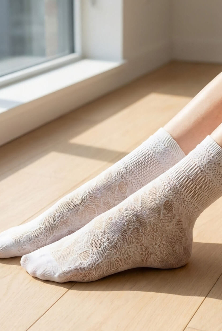 Sheer Floral Lace Crew Socks in white with fine floral lace knit, shown in a close-up on a wooden floor in natural light, emphasizing the sheer construction and soft, breathable material.