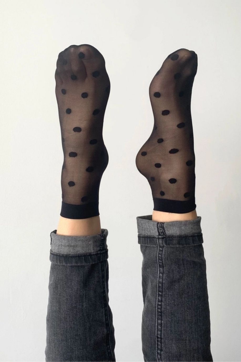 2-Pack Sheer Polka Dot Socks featuring a sheer black knit with evenly spaced polka dots and comfortable stretch band, worn with both feet lifted straight, showcasing full coverage and clean silhouette against a neutral background.