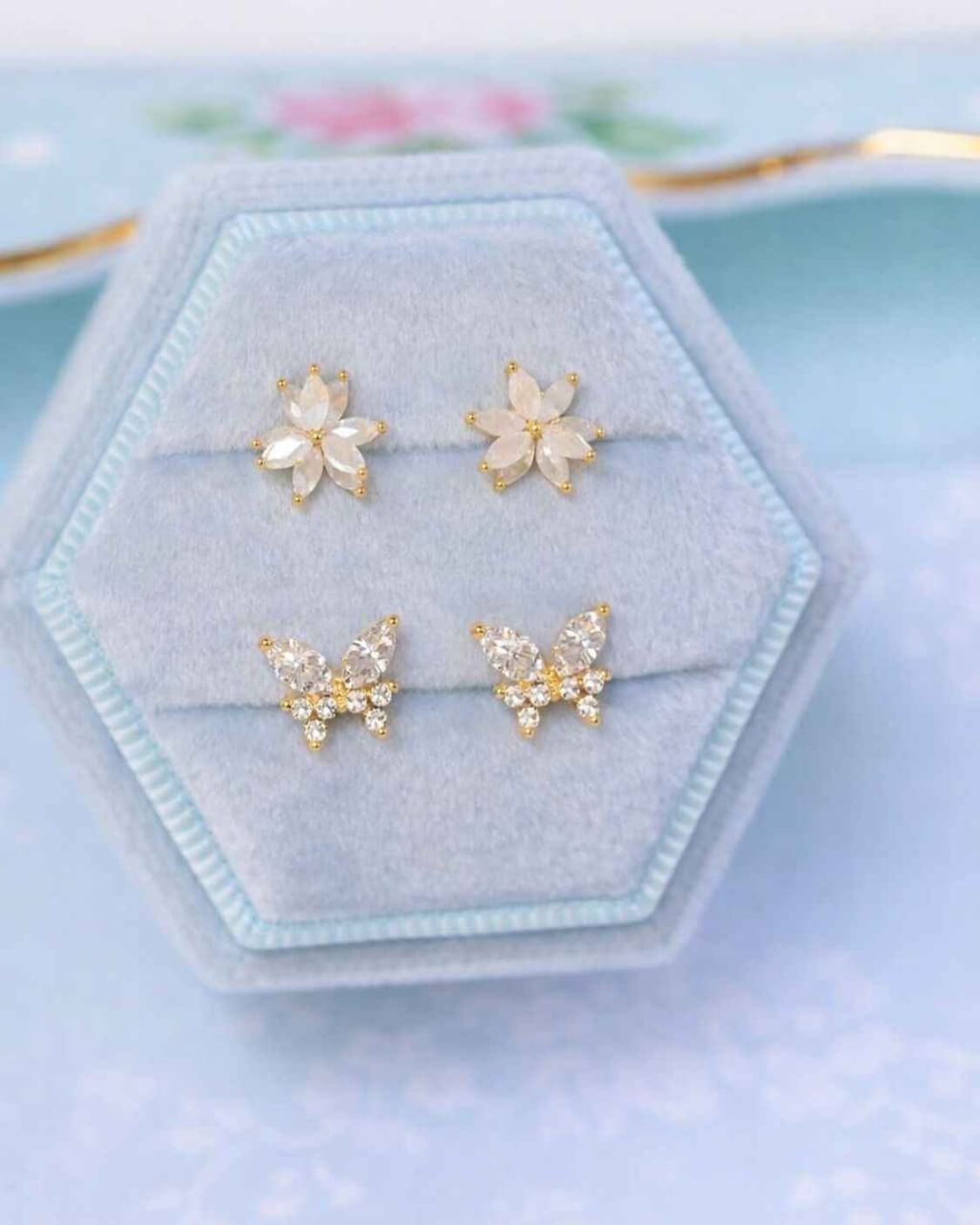 Remember Me Butterfly Studs featuring butterfly shaped crystal studs with marquise stone accents and polished gold tone detailing, displayed in a velvet jewelry presentation box alongside matching floral studs, highlighting elegant sparkle and gift ready presentation.