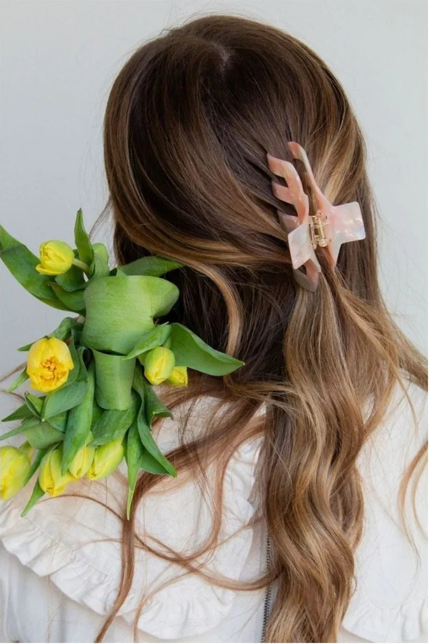 Woman with wavy brown hair wearing a pink hair claw, holding yellow tulips, Love Classic style
