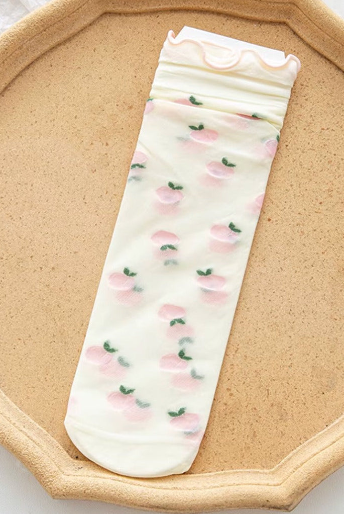 Sheer mesh crew socks with a pastel pink plums pattern and a soft lettuce-edge cuff on a neutral background.