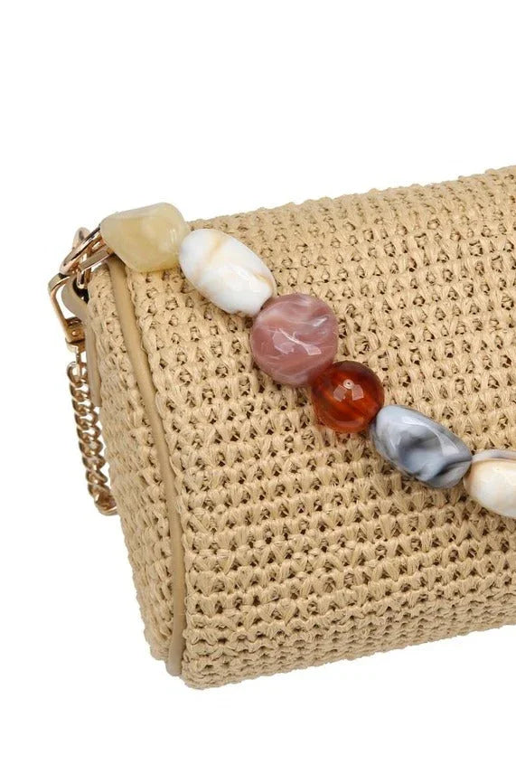 Close-up of the natural Rachel Straw Clutch showcasing the detailed straw weave, sculptural bead embellishments, and secure zip-top finish.