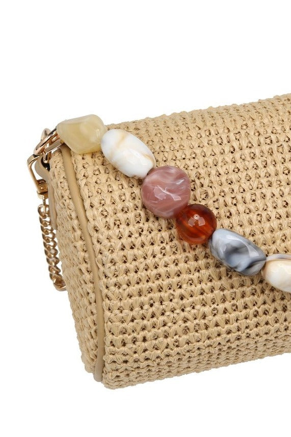 Close-up of the natural Rachel Straw Clutch showcasing the detailed straw weave, sculptural bead embellishments, and secure zip-top finish.