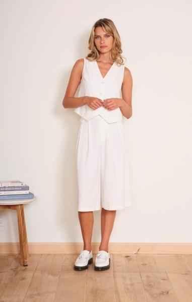 Woman in sleeveless white vest and knee-length culottes from Love Classic, standing indoors