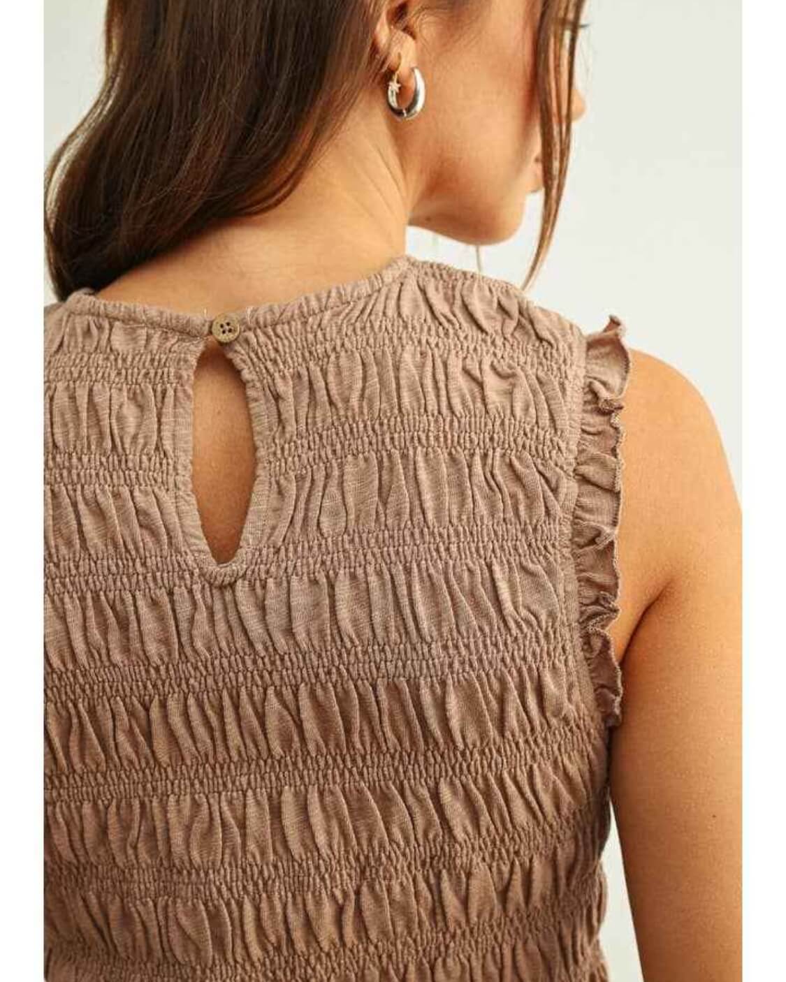 Sleeveless with All Over Smocking Top featuring detailed smocked stitching with a back keyhole button closure and soft ruffle sleeve edges, captured in a close up rear angle against a neutral backdrop, highlighting gathered texture and refined finishing details.
