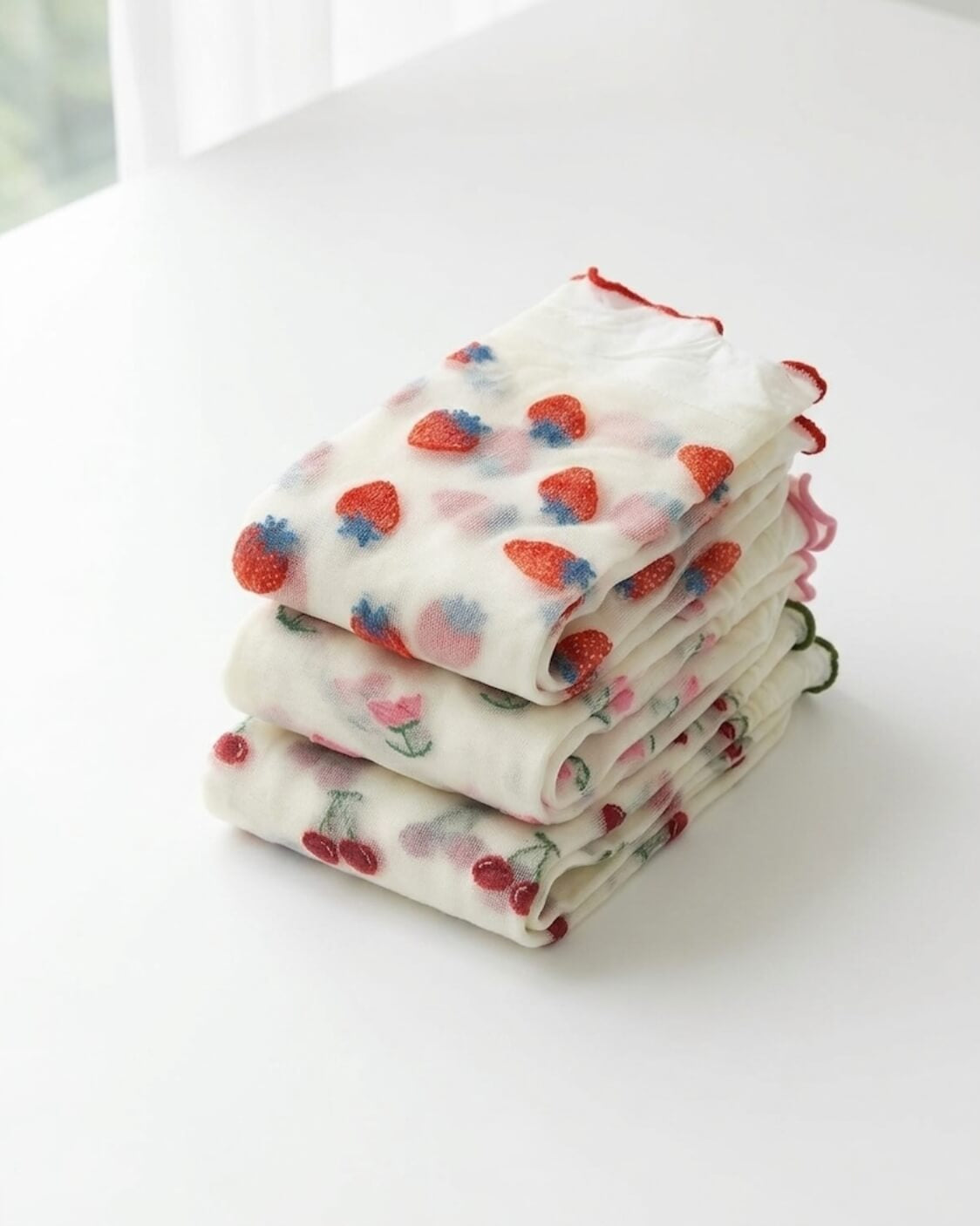 Whimsical Ruffle Edge Sheer Socks bundled pack featuring assorted fruit and floral embroidered patterns with soft sheer fabric and ruffle edge cuffs, neatly folded on a clean white surface to showcase the variety and lightweight texture.