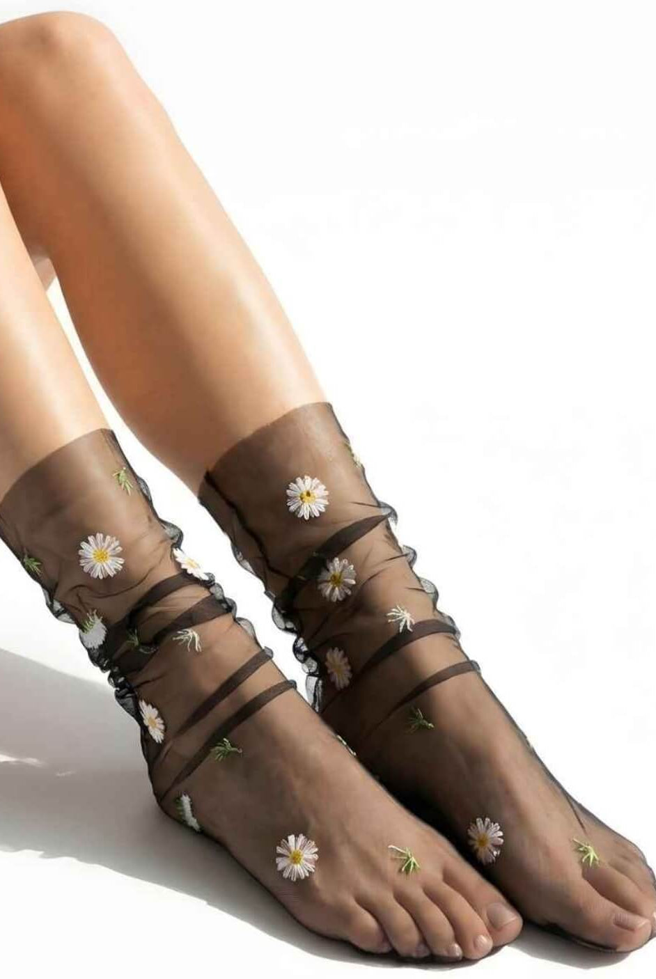 Sheer Garden Daisy Crew Socks in black sheer mesh with white and yellow daisy embroidery, displayed on feet to emphasize contrast and pattern.