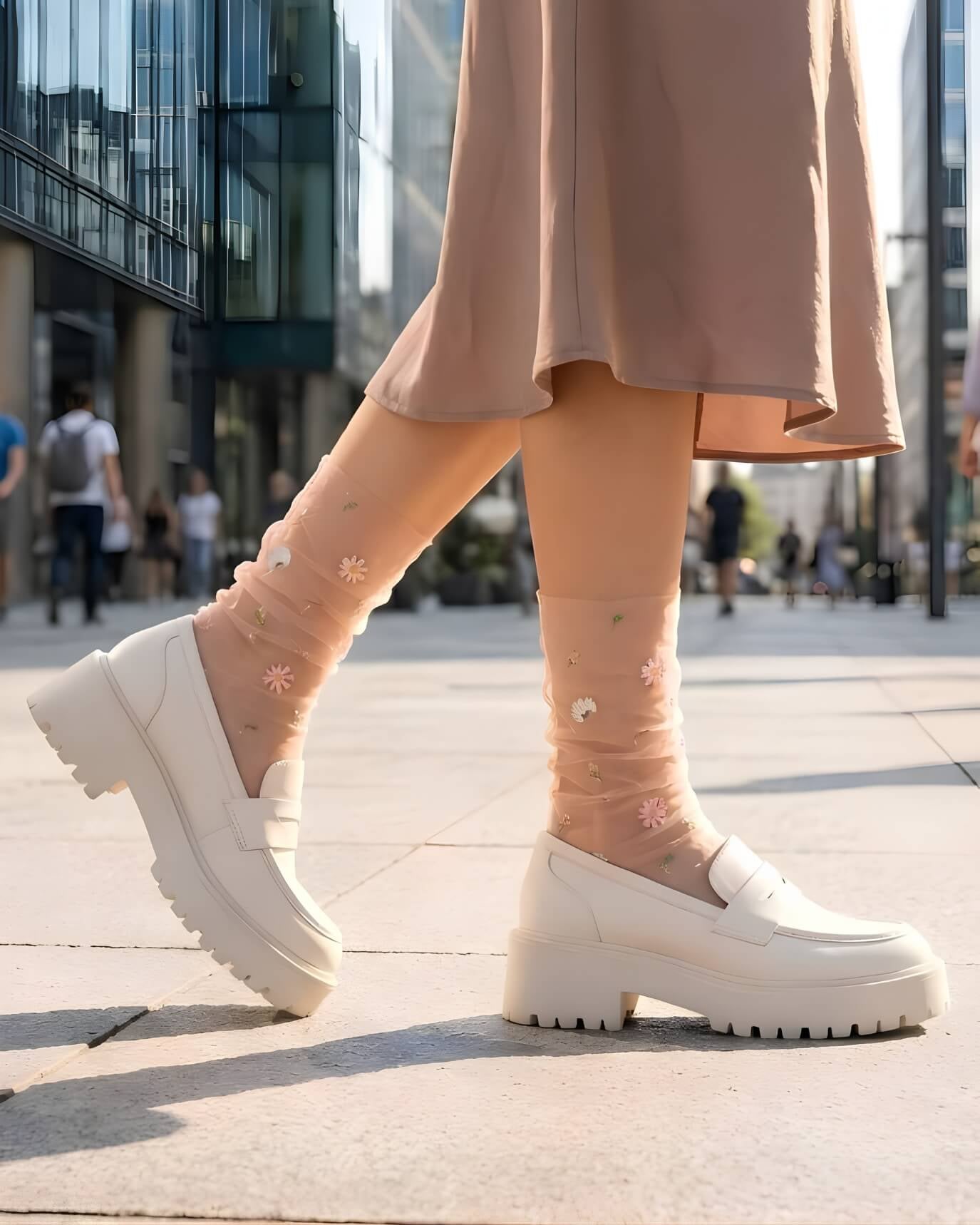 Sheer Garden Daisy Crew Socks in nude with daisy embroidery, styled with white platform loafers in an outdoor city setting for a casual look.