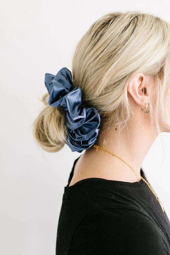 Blonde woman wearing large blue satin scrunchie in low bun, Love Classic hair accessory style