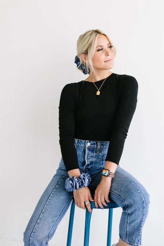 Woman in stylish black top and blue jeans with scrunchie, Love Classic fashion style