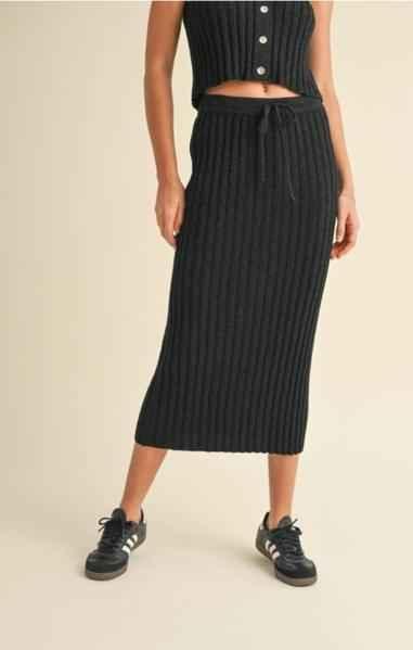 Woman wearing a ribbed black knit midi skirt and matching crop top from Love Classic